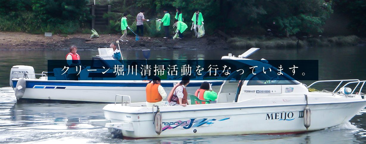 堀川の岸辺で清掃活動をする社員